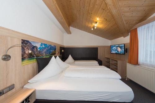 a bedroom with two beds and a tv at Appartements Schneezauber in Lermoos