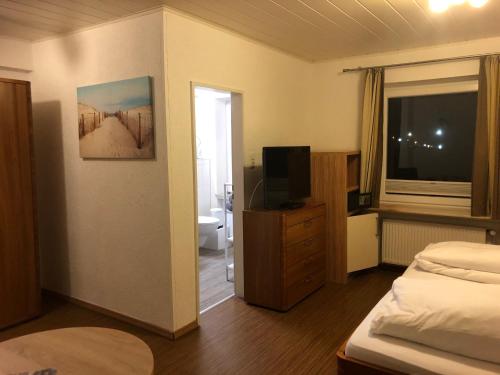 a room with a bedroom with a bed and a television at Heeren's Hotel Garni in Bensersiel