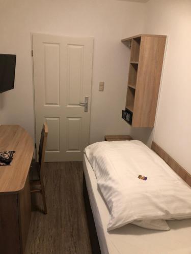 a bedroom with a bed and a desk and a door at Heeren's Hotel Garni in Bensersiel
