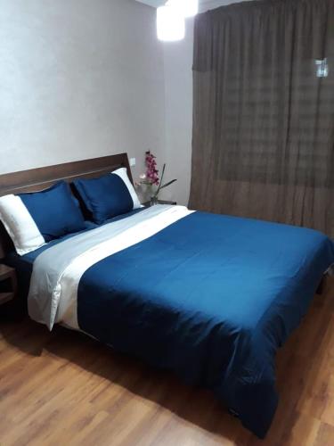 a bed with a blue comforter in a bedroom at Nouaceur Garden Comfort and Serenity Casa Airport in Nouaseur