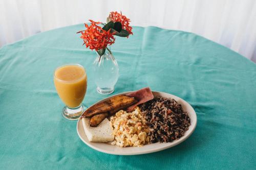 un tavolo con un piatto di cibo e un bicchiere di succo d'arancia di Hotel Javy a Liberia
