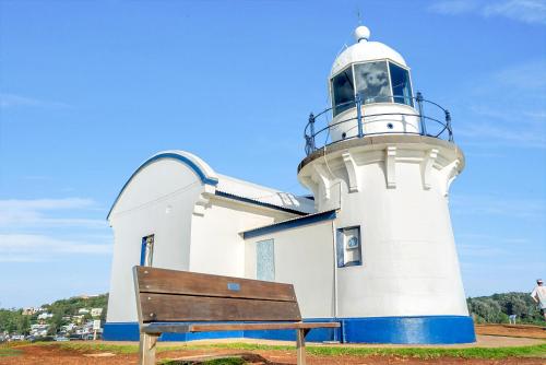 a wooden bench in front of a lighthouse at Surf Beach Motel Port in Port Macquarie