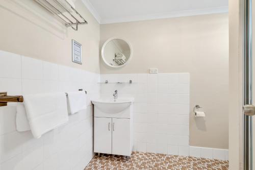a white bathroom with a sink and a mirror at Surf Beach Motel Port in Port Macquarie