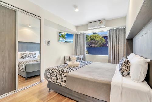 a hotel room with a bed, desk and a painting on the wall at Surf Beach Motel Port in Port Macquarie
