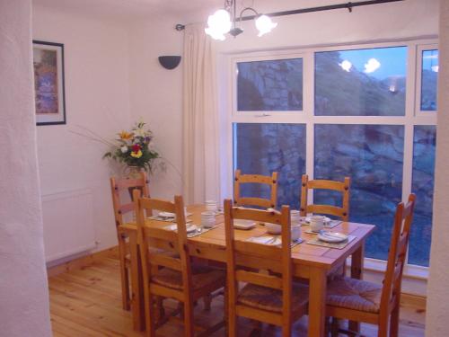 d'une salle à manger avec une table, des chaises et une fenêtre. dans l'établissement Crohy Cottage, à Donegal