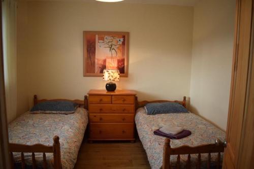 a bedroom with two beds and a lamp on a dresser at Teach Barney in Falcarragh