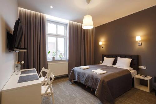 a bedroom with a bed and a desk and a window at PRZYSTANEK KATOWICE Mariacka 26 in Katowice