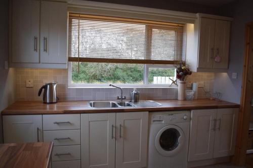 een keuken met een wastafel en een wasmachine bij Teach Barney in Falcarragh