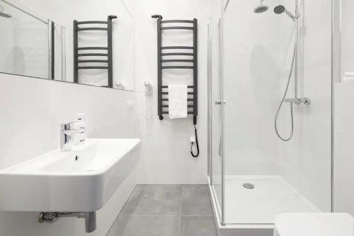 La salle de bains blanche est pourvue d'un lavabo et d'une douche. dans l'établissement Przystanek Katowice Mariacka 26, à Katowice