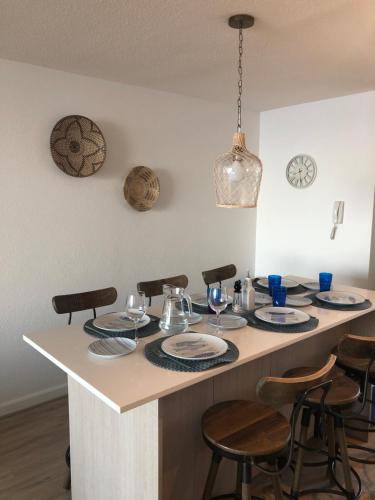 una isla de cocina con una mesa con platos y copas de vino en Punta Puyai - Departamento Nuevo primera línea en Papudo