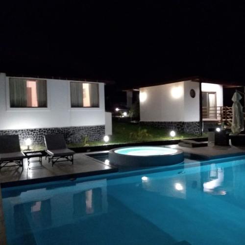 a swimming pool with two chairs and a house at Hotel Villa Sirena in Vichayito