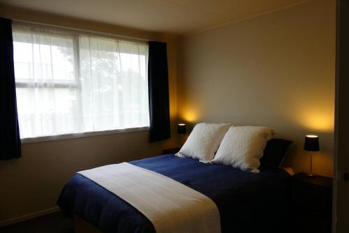 a bedroom with a bed with two pillows and a window at Walnut Cottage, Turangi/Tongariro in Turangi