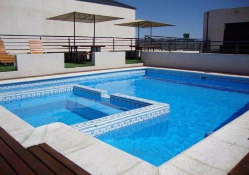 a swimming pool with blue water in front of a building at Departamento Carlos Paz, Centro in Villa Carlos Paz
