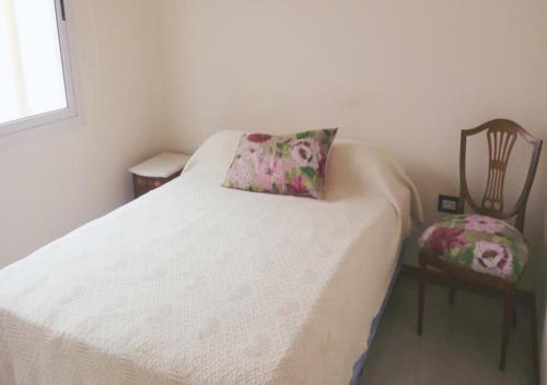 a bed with a pillow and a chair in a room at Departamento Carlos Paz, Centro in Villa Carlos Paz