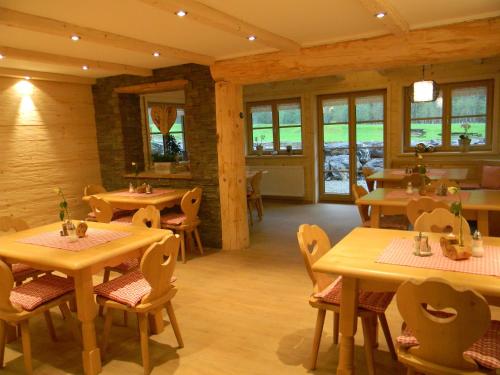 a restaurant with wooden tables and chairs and windows at Landhaus Spielmannsau in Oberstdorf