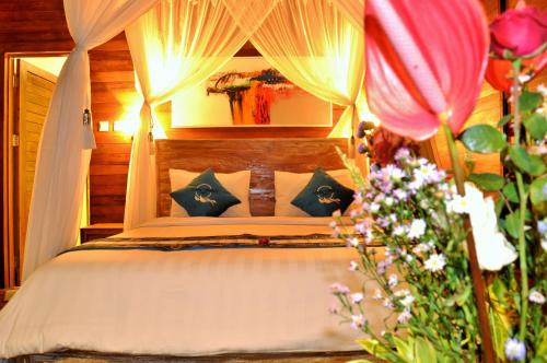 a bedroom with a bed with a canopy and flowers at Ocean Terrace Suite And Spa Luxury in Nusa Penida