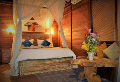 a bedroom with a canopy bed and a table with flowers at Ocean Terrace Suite And Spa Luxury in Nusa Penida