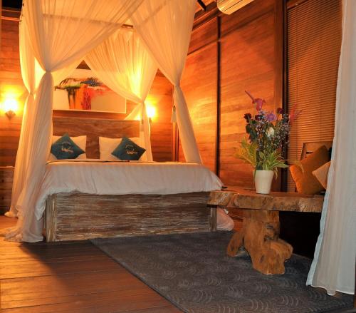a bedroom with a canopy bed with a table and flowers at Ocean Terrace Suite And Spa Luxury in Nusa Penida