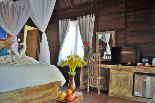 a bedroom with a bed and a desk with a television at Ocean Terrace Suite And Spa Luxury in Nusa Penida