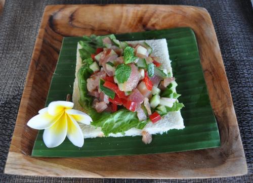 a plate of food with a salad on a banana leaf at Ocean Terrace Suite And Spa Luxury in Nusa Penida