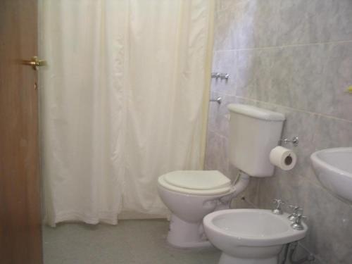 een badkamer met een wit toilet en een wastafel bij Cabañas Rosales de Punilla in Huerta Grande