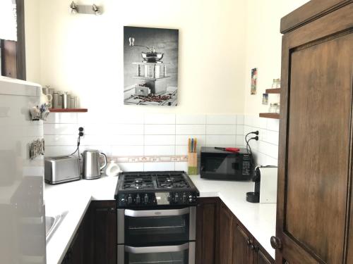 a kitchen with a stove and a microwave at Casa Felina Apartment in Wellington