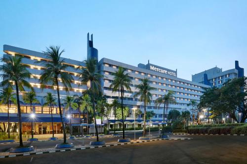 a hotel with palm trees in front of it at Mercure Convention Center Ancol in Jakarta