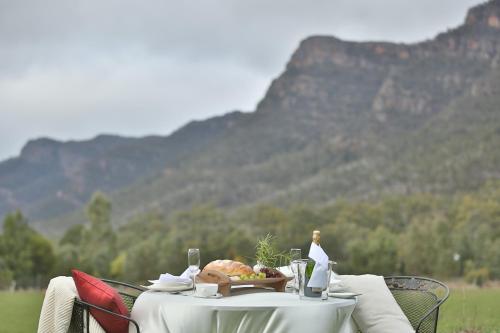 a table with a plate of food on it with mountains in the background at Ironstone Romantic Couples Retreat in Halls Gap