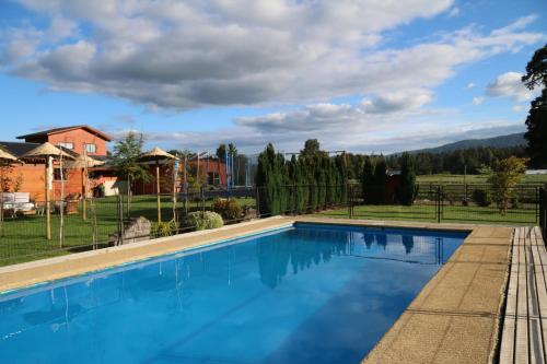 a swimming pool with a view of a house at Cabañas de la Barra in Villarrica