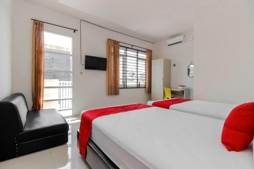 a bedroom with two beds and a window and a chair at RedDoorz at Tara Homestay Palembang in Palembang