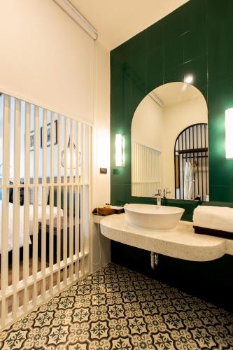a bathroom with a sink and a bed and a mirror at Chaanburi Boutique Resort in Chanthaburi
