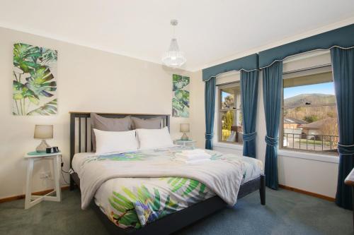a bedroom with a bed with blue curtains and a window at Abbey Rose - Bright, VIC in Bright