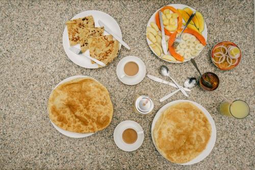 a table topped with plates of food with pancakes and fruit at Kalyan Heritage in Jaipur