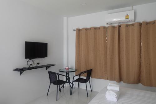 a room with a table and two chairs and a television at Airport Pearl Residence in Nai Yang Beach