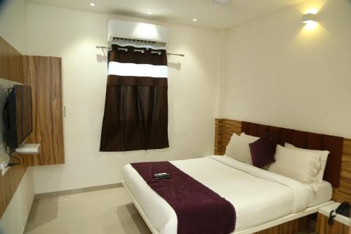 um quarto de hotel com uma cama e uma janela em Shree Akshar Restaurant and Hotel em Ahmedabad