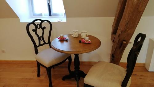 a wooden table with two chairs and cups on it at L'Amalgam' in Ainay-le-Vieil