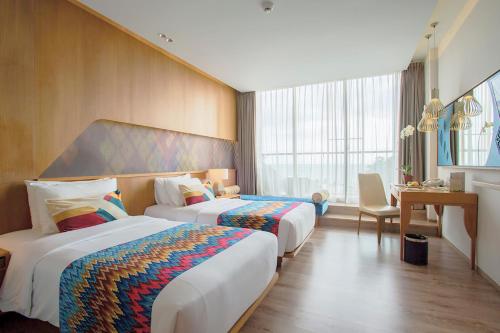 a hotel room with two beds and a desk at Aruna Senggigi Resort & Convention in Senggigi 