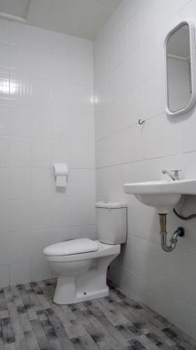 a white bathroom with a toilet and a sink at Kathleens Vacation Place in Moalboal