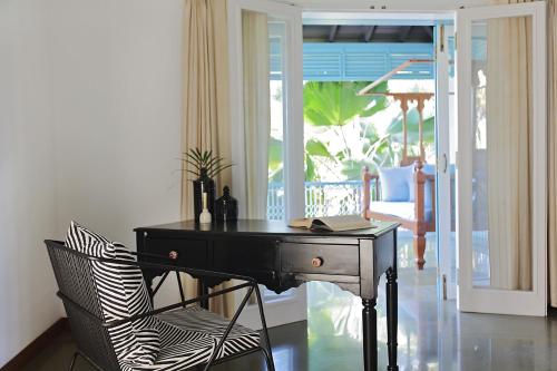 a black desk and a chair in a living room at Assagao Bay by the Rose Nomad in Assagao