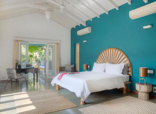 a bedroom with a white bed and a blue wall at Assagao Bay by the Rose Nomad in Assagao