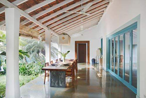 a dining room with a long table with chairs at Assagao Bay by the Rose Nomad in Assagao