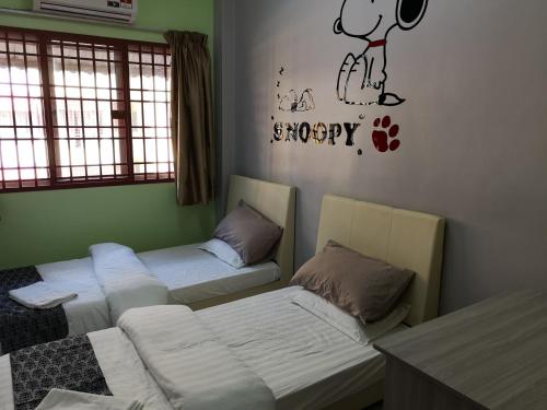 a room with two beds with a mickey mouse sticker on the wall at Kelly Cozy cottage in Kampar