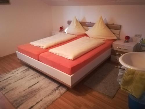 a bedroom with a bed with orange and white sheets at Landhaus Irma in Bad Füssing