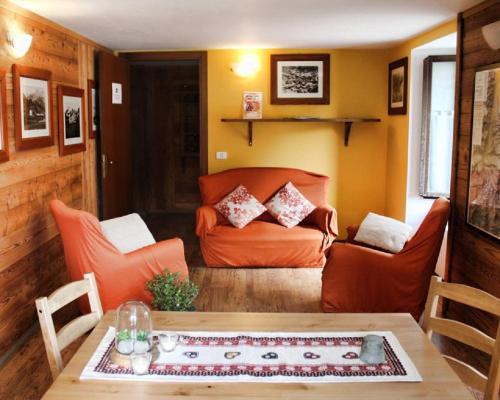 a living room with an orange couch and a table at Indren Hus in Alagna Valsesia