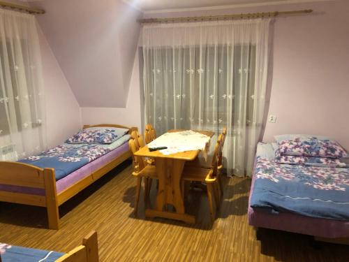 Nowe BystreにあるPokoje Gościnne Pod Gubałówkąのベッド2台、木製テーブル、デスクが備わる客室です。