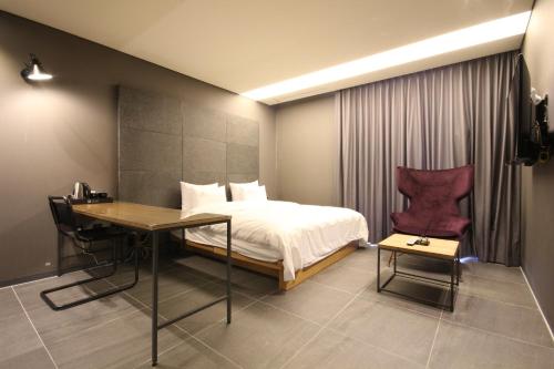 a bedroom with a bed and a desk and a table at Hotel Eco stay in Jeonju