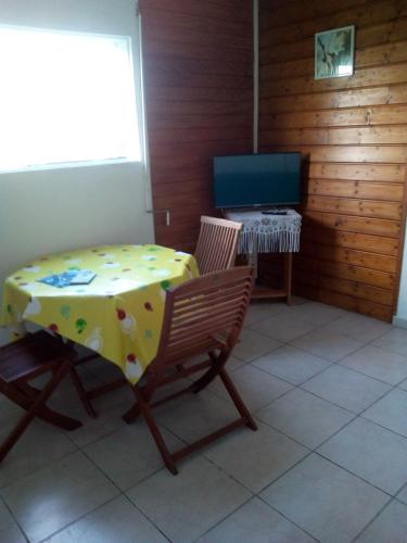 a table and chairs in a room with a television at Très belle location touristique in Sainte-Anne