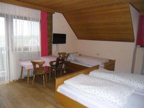 una habitación con cuatro camas y una mesa y sillas en Pension Elsendorf, en Elsendorf