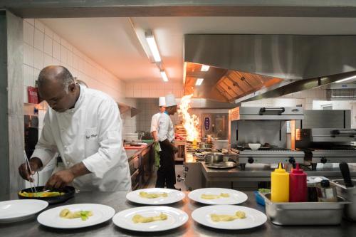 two chefs in a kitchen preparing food on white plates at Seasense Boutique Hotel & Spa in Belle Mare