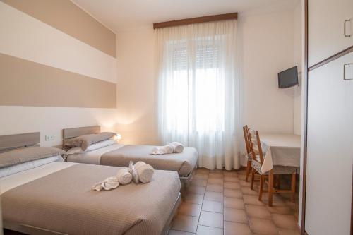a room with three beds and a table and a window at Residenza Miola in Saronno